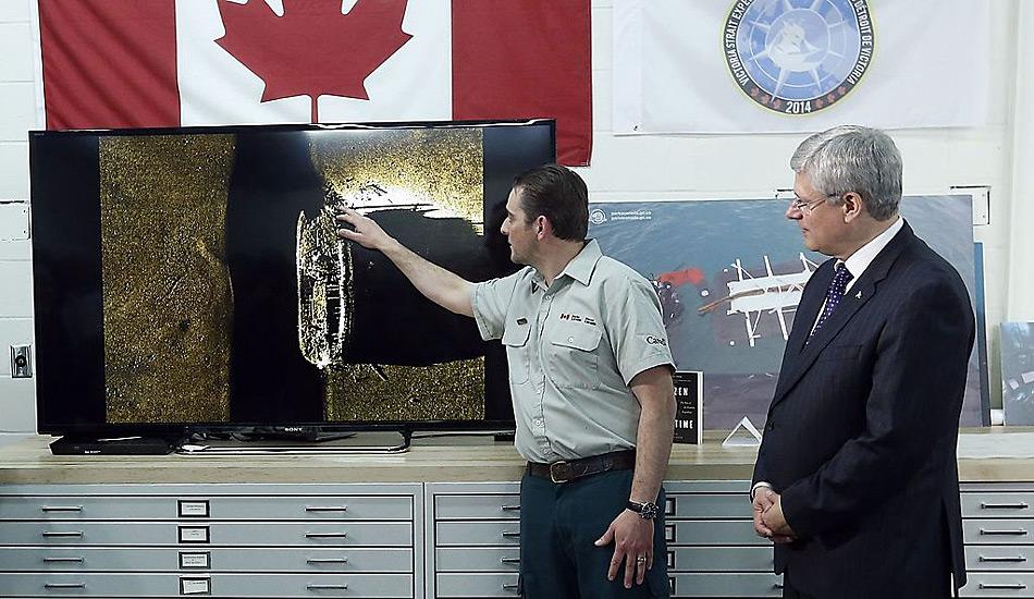 Kanadas Premierminister Stephen Harper beobachtet wie Parkranger Ryan Harris die Entdeckung eines von zwei Schiffen aus der Franklin-Expedition am 9. September in Ottawa erklärt.