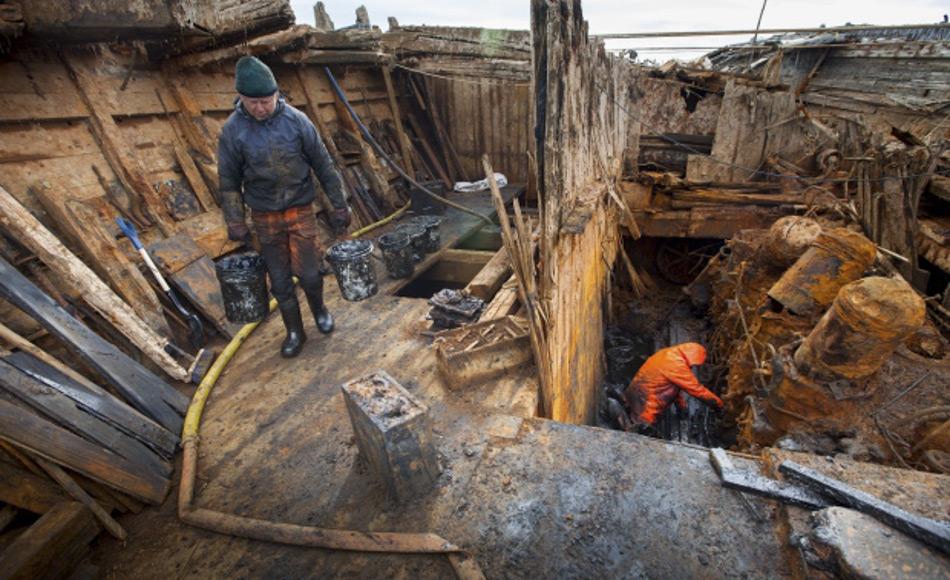 Stig Pettersen trägt eine grosse Portion Schlamm aus der Maud, während Terje Morved den alten Motor freilegt. Bild: Jan Wanggaard